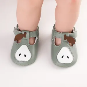 Gros plan de chaussures de premiers pas pour bébé vert sauge avec un motif de poire.