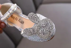Close-up detail of silver rhinestone rabbit head on girls' princess flat shoes.