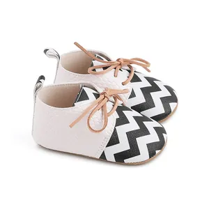 Close-up detail of infant walking shoes with black and white zigzag pattern and tan laces
