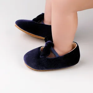 Detalle de zapatos de princesa para bebé en terciopelo azul marino con lazo y correa