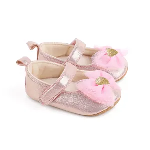 Close-up detail of pink glitter baby princess shoes with mesh bow and golden heart decoration