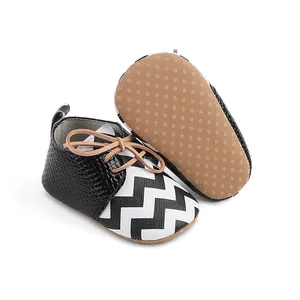 Close-up detail of infant walking shoes with black chevron pattern and tan non-slip sole dots