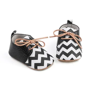 Close-up of newborn baby walker shoes featuring black white zigzag pattern and tan laces