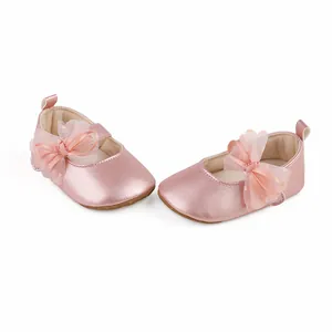Detailed view of pink metallic baby princess shoes with a decorative tulle bow decoration.