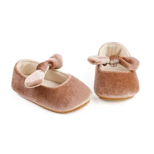 Primer plano de zapatos de princesa para bebé en terciopelo malva con detalle de lazo