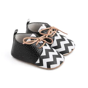Close-up of baby walking shoes with black snake texture and chevron pattern