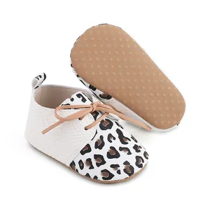 Detailed view of white and leopard print infant walking shoes featuring non-slip dotted soles