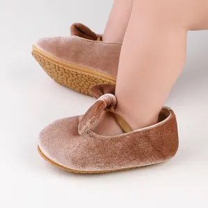 Primer plano de zapatos de bebé en terciopelo marrón con un lazo y suela de textura