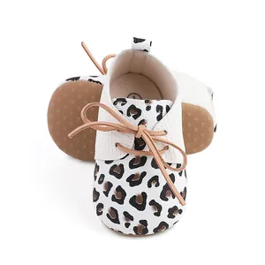 Detailed view of white leopard print baby pre-walker shoes featuring brown lace-up bow