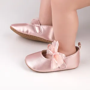 Primer plano de zapatos de bebé rosa metalizado con un lazo de tul rosa decorativo