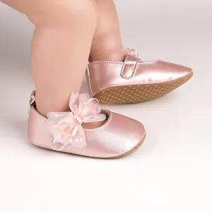 Vista detallada de zapatos de bebé rosa metalizado con lazo de encaje y suela antideslizante.