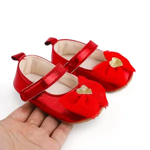 Macro view of red baby girl princess dress shoes featuring a bow and gold heart