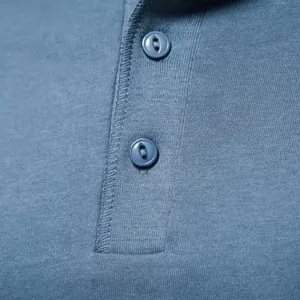 Nahaufnahme der Knopfleiste und der feinen Stricktextur eines blauen Henley-Shirts