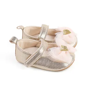 Detail view of gold infant princess shoes featuring a pink lace bow and gold heart