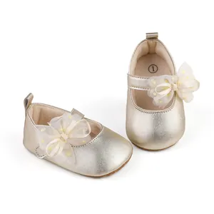 Close-up of gold baby Mary Jane shoes with delicate yellow tulle bow detail
