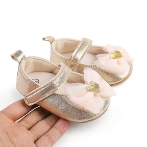 Close-up of gold metallic baby princess shoes with pink tulle bow details