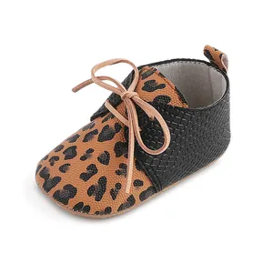 Close-up detail of leopard print and black faux-leather baby walker shoes with laces