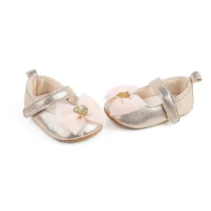 Detailed view of champagne gold baby princess shoes with pink tulle bow and glitter heart.