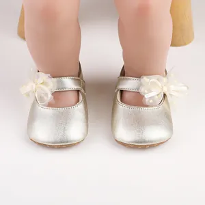 Macro view showing the texture of gold metallic baby shoes with a delicate mesh bow