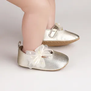 Detalle de zapatos dorados para bebés con lazo de tul blanco en pies infantiles