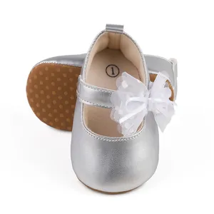 Zapatos de bebé plateados con un lazo de malla blanca y suela antideslizante.