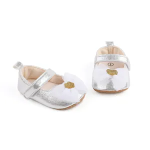 Detailed macro view of silver baby princess shoes with mesh bows and gold hearts.