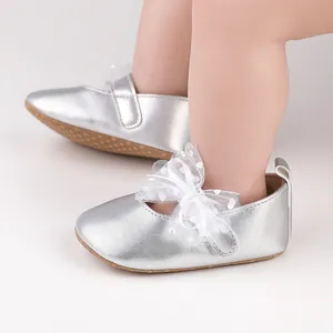 Detalle de los zapatos plateados para caminar de bebé con un lazo de encaje blanco