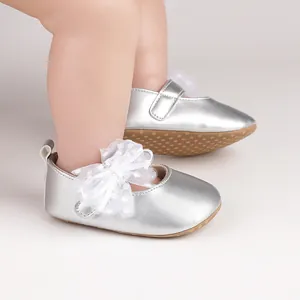 Detalle de los zapatos plateados para bebé con lazo de malla y lunares blancos