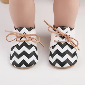 Close-up of black and white chevron baby walking shoes with rubber anti-slip soles.
