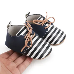 Close-up of navy blue and white striped baby walking shoes with tan laces.