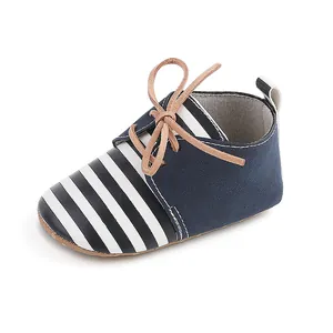 Close-up of navy blue and white striped infant pre-walker shoes with tan laces