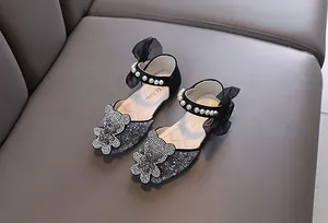 Gros plan de chaussures de princesse noires pour filles avec ours en strass et perles