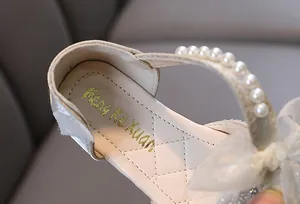Gros plan de chaussures de princesse pour filles avec bride en perles et semelle d'or