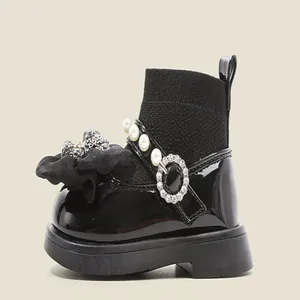 Detalle lateral de botines tipo calcetín de charol negro para bebé con perlas y brillos
