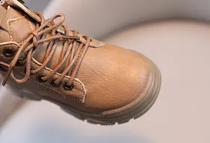 Detailed close-up showing the brown faux leather texture and laces of kids' Martin boots.