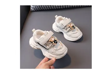 Close-up of children's beige chunky sneakers featuring a cute bear accessory