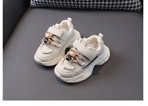 Detail view of children's beige chunky sneakers featuring a cute bear ornament on laces