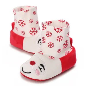 Detalle de patucos festivos de algodón para bebé con copos de nieve y diseño de nariz roja