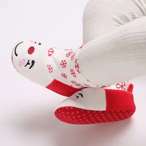 Primer plano de botas de nieve para bebé con diseño de Papá Noel de felpa y copos de nieve