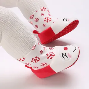 Primer plano de patucos navideños para bebé con bordado de Papá Noel y copos rojos