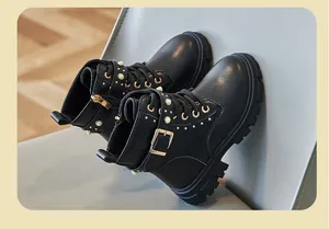 Close-up of black girls' Martin boots featuring gold buckles and pearl accents.