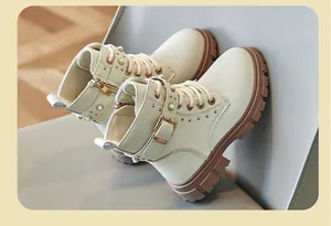 Detailed view of cream children's Martin boots with gold buckles and pearl accents