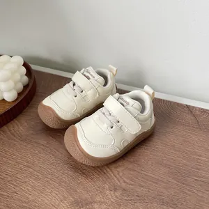 Close-up detail of cream baby walking shoes featuring soft soles and velcro straps