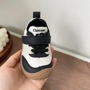 Close-up detail of black and white baby walking shoe featuring velcro strap and soft sole