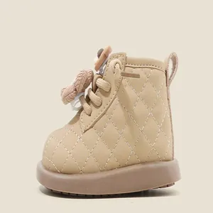 Vue latérale des bottes en cuir matelassé beige pour bébés avec un joli détail d'ours