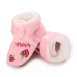 Detail of pink plush baby boots with embroidered strawberry and HAPPY text decoration