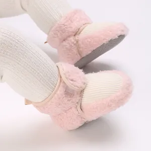 Close-up detail of soft pink plush baby winter boots with textured anti-slip soles