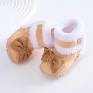 Nahaufnahme von Plüsch-Babyschuhen mit weißem Kunstpelz und dekorativer brauner Schleife.