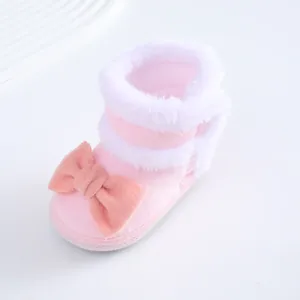 Seitenansicht der weichen rosa Plüsch-Babyschuhe mit weißem Kunstfellbesatz und Schleife