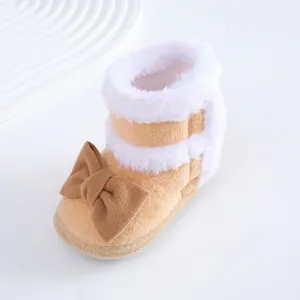 Nahaufnahme von Plüsch-Babystiefeln mit brauner Schleife und weißem Kunstfell